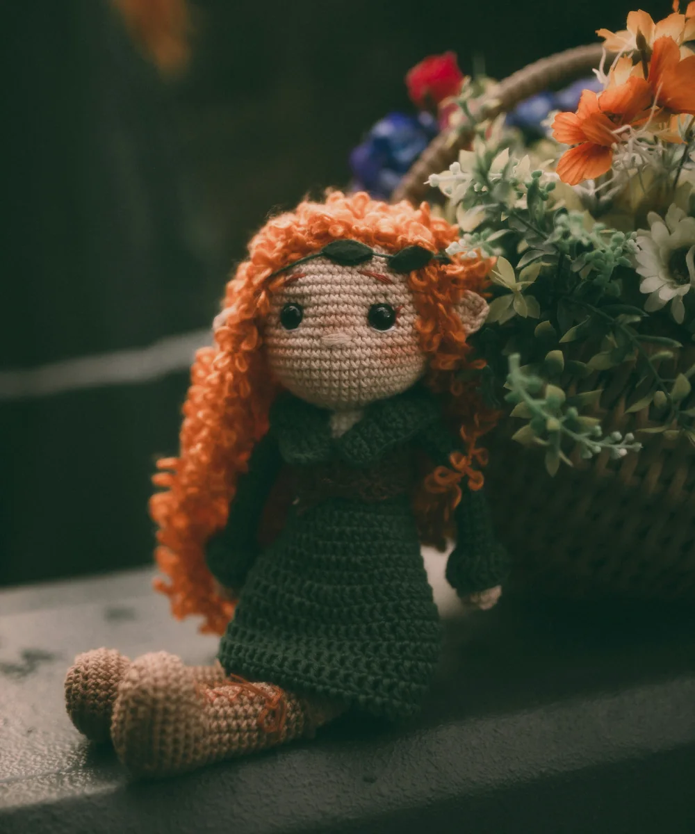Crocheted animal-like companion among flowers.