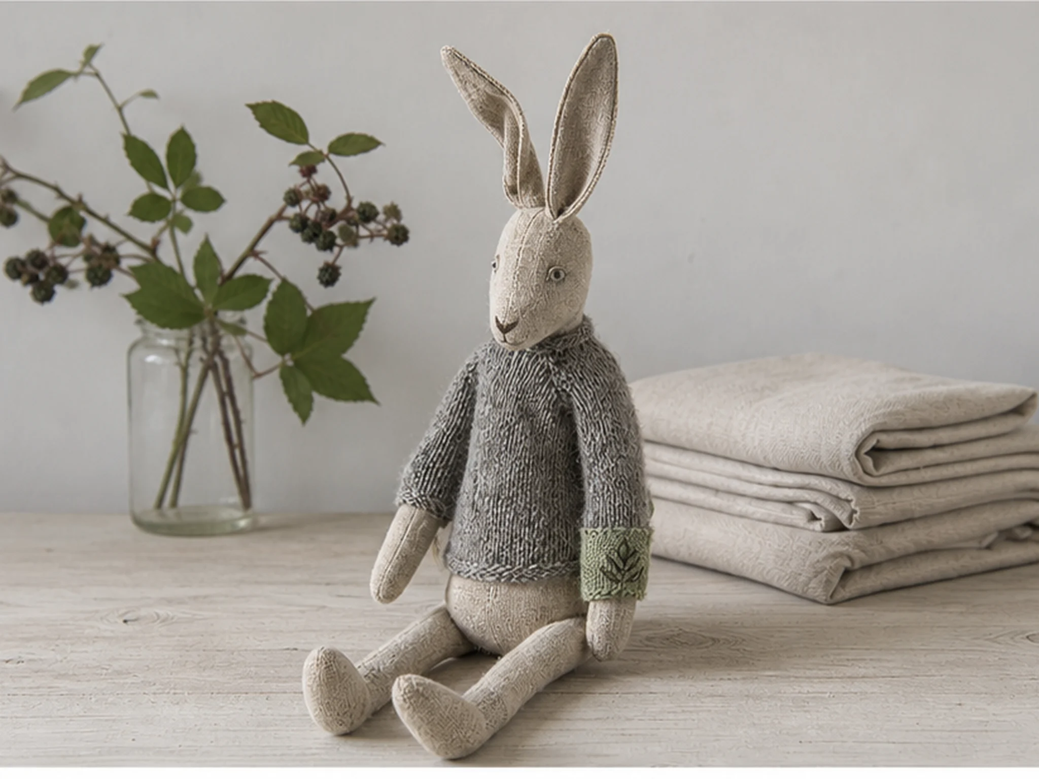 Bramble Rabbit, a long-eared linen rabbit in a lichen-green hand-knit sweater.