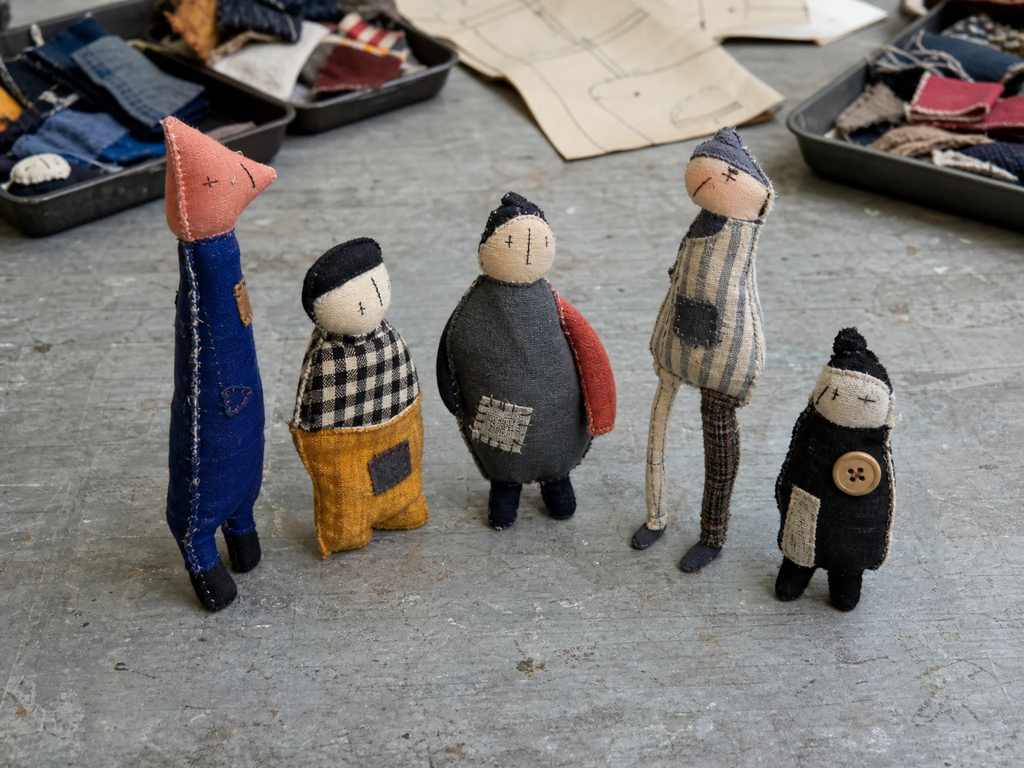 Five differently proportioned miniature cloth figures arranged as a small collection.