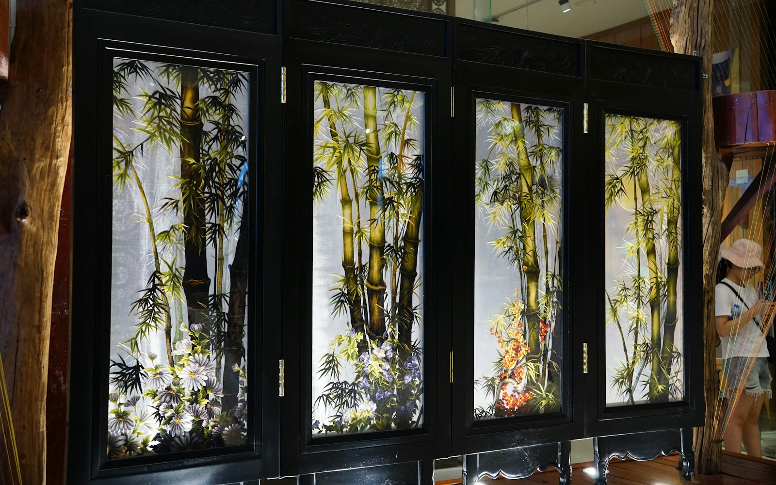 A handmade mixed-media textile art doll displayed inside a glass cabinet with clear space around embroidered clothing and wire details.