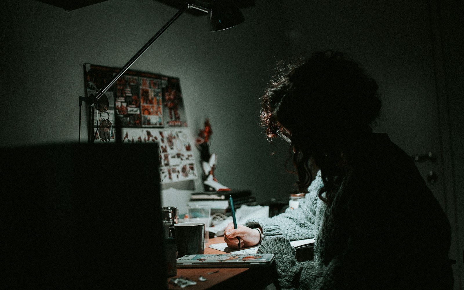A handmade art doll beside a notebook, measuring tape, archival-style labels, and a camera on a worktable.