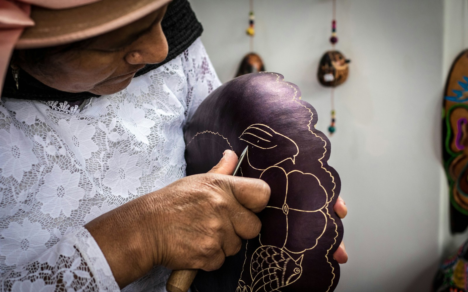 Close view of hands embroidering small facial details onto a lightly padded cloth art doll face with fine thread and needle.
