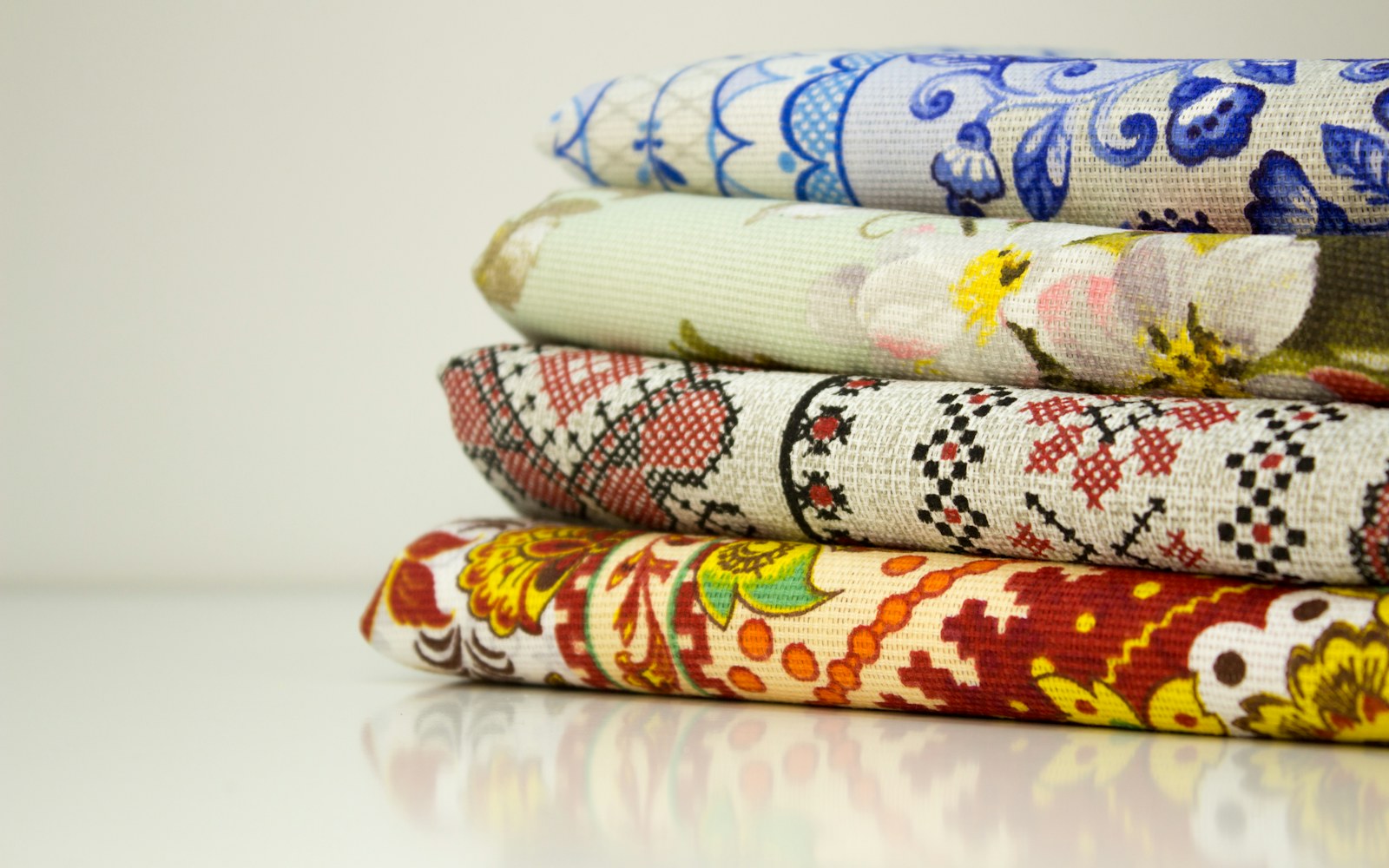 Assorted thrifted fabric scraps, paper pattern pieces, thread, and small handmade doll clothing arranged on a worktable.