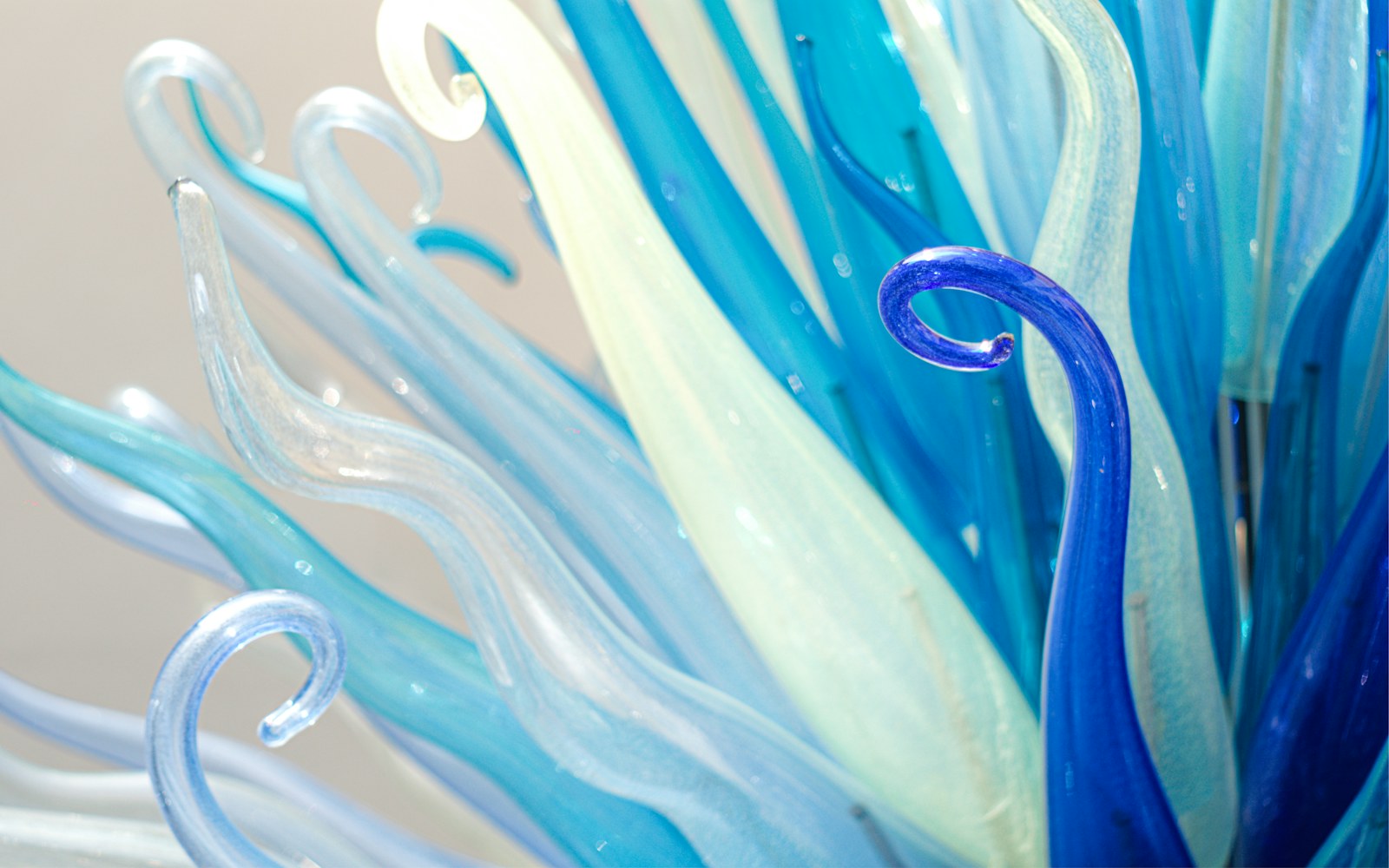 Close view of a handmade art doll with delicate translucent glass details supported on a stable display stand.