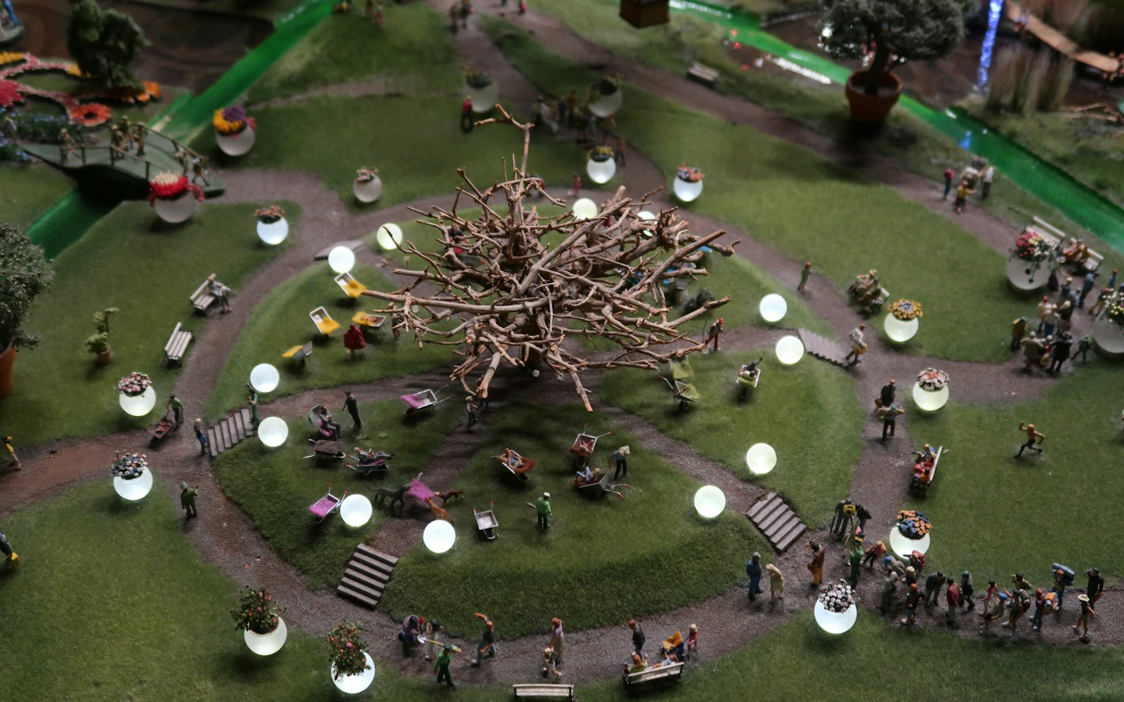 A handmade miniature room diorama with a small warm LED lamp, visible wire-routing channel, and an open access panel in its base.
