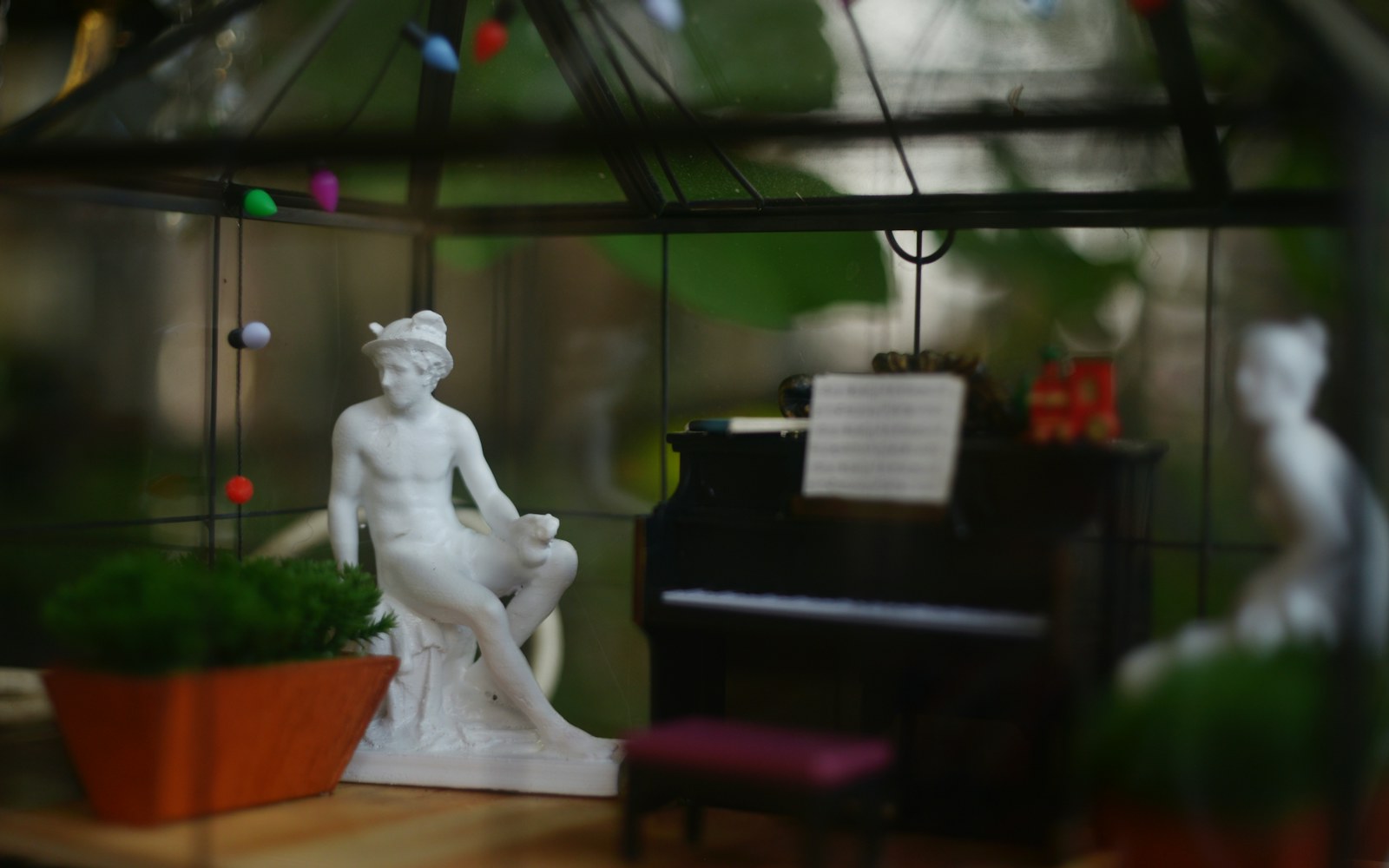 A handmade miniature room diorama on a worktable, softly lit with concealed LED lights and an open rear access panel.