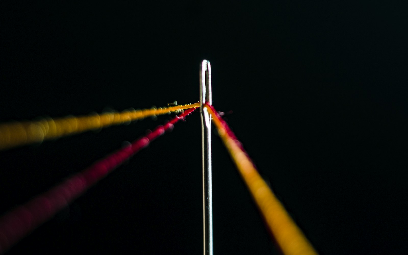 Close view of a small hand-stitched white needle-lace collar on a protected paper pattern beside fine thread and needles.