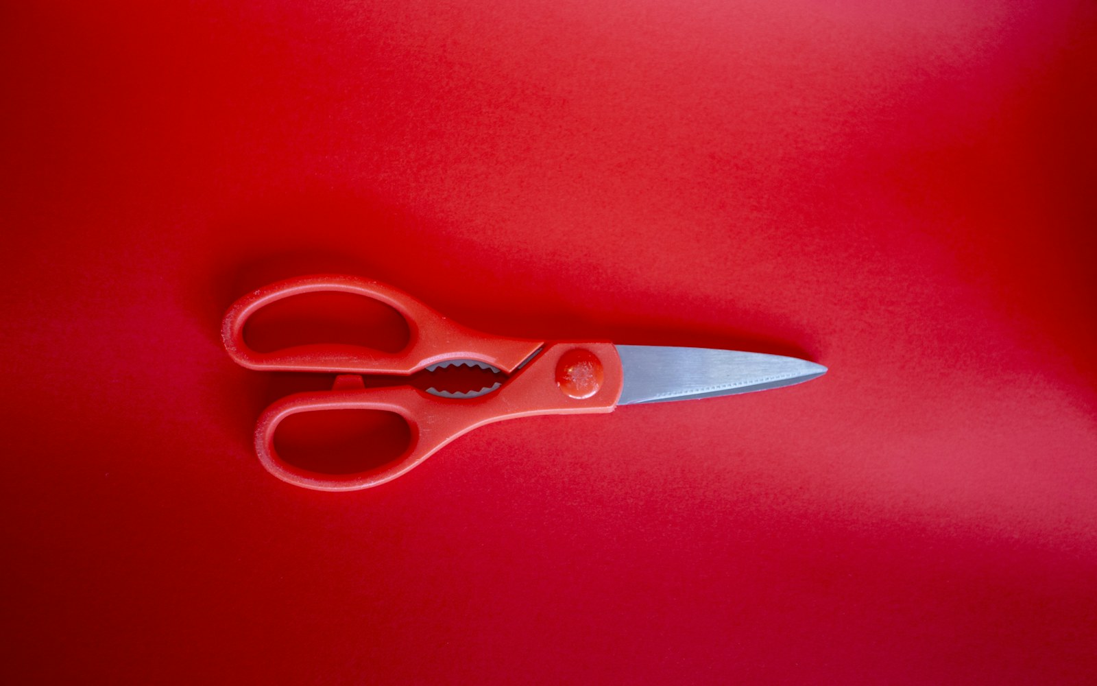 A pair of sharp embroidery scissors resting on a piece of fabric next to a small doll garment