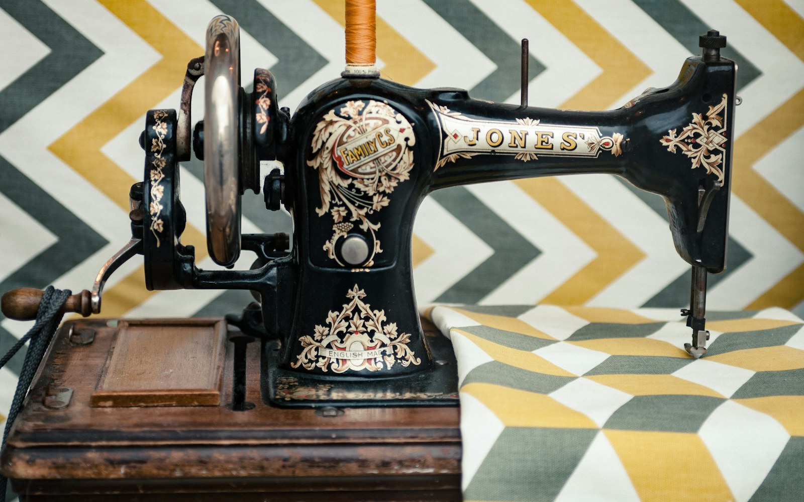 Close view of hands assessing a folded sentimental garment beside doll pattern pieces, fabric swatches, a notebook, and sewing tools on a worktable.