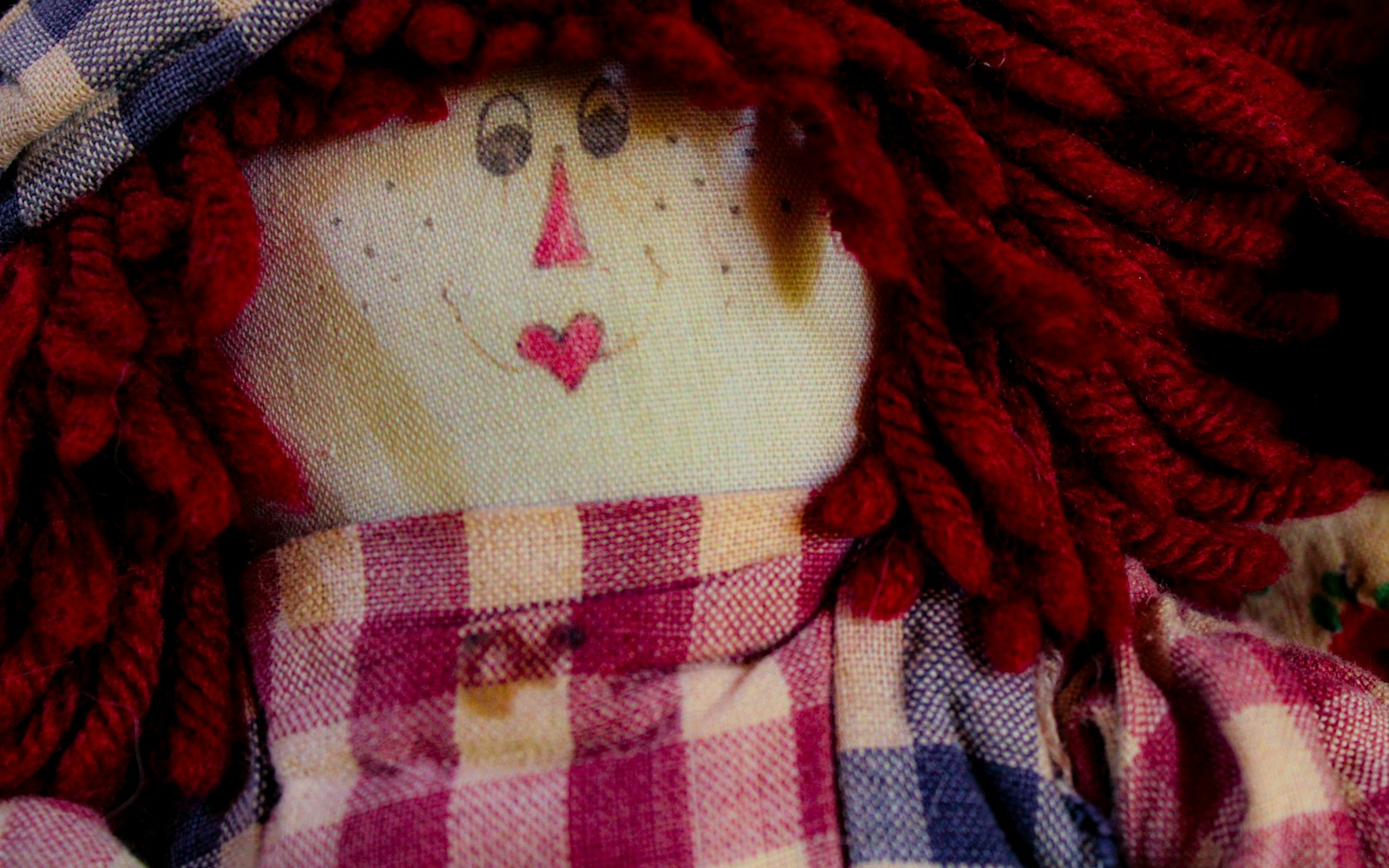 Close-up of a hand-stitched seam on a cloth doll with uneven stitches and a small stain, emphasizing handmade character.