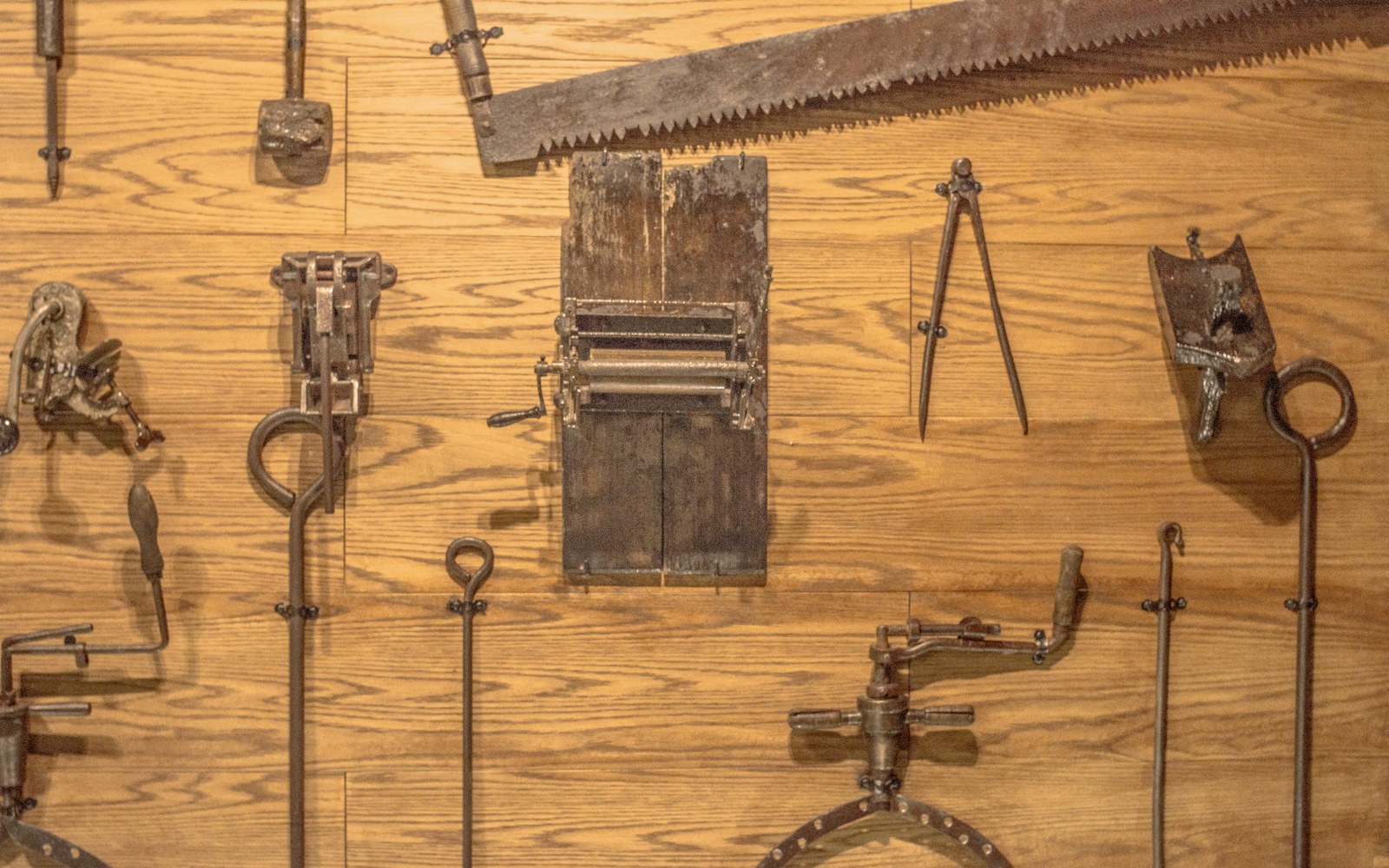 Close view of a small wire armature for a textile doll on a worktable, with wrapped joints, soft padding, thread, fabric, and hand tools.