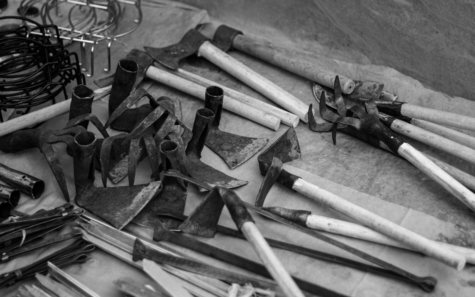 Close view of a handmade wire armature for a small doll beside cutters, pliers, soft padding, and a paper body template on a worktable.