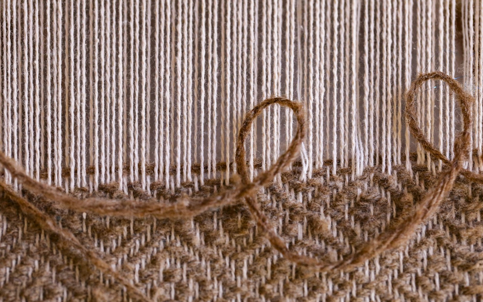 Close view of a small textile doll armature wrapped in soft padding beside fabric, thread, embroidery tools, and wire cutters.